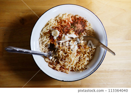 Tradition Thai food Hot and spicy Seafood instant noodle in white bowl with fork and spoon on wooden floor background 113364040