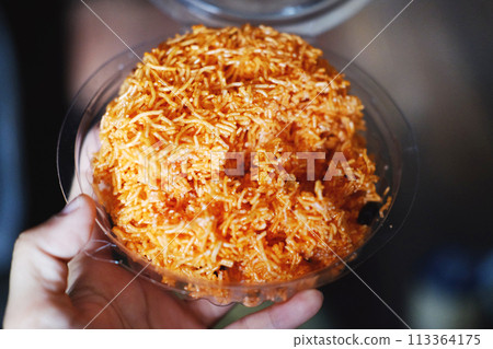 Hand holding Sweet & Sour crispy rice noodle vermicelli in clear plastic box 113364175