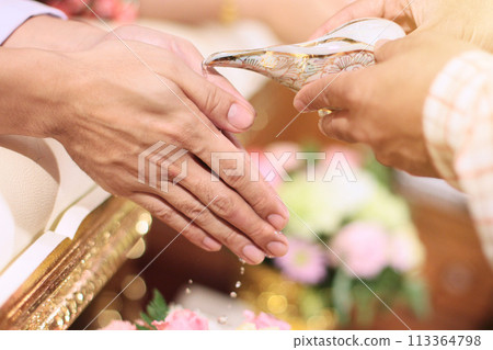 Hand pouring water from conch shell to bless the groom and the bride in tradition Thai wedding ceremony 113364798