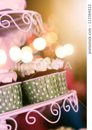 Wedding Cupcakes with colorful sprinkles in green cup with garland lights bokeh background 113364815