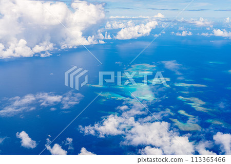 In-flight resort summer vacation travel airplane sea wing inbound window clouds island beach coral In-flight resort summer vacation travel airplane sea wing inbound window clouds island beach coral 113365466
