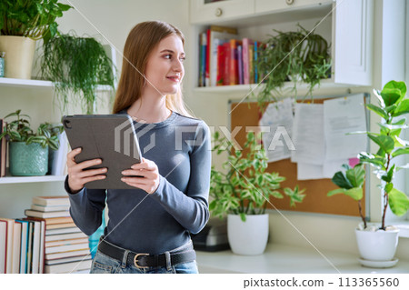 Young teenage female using digital tablet, home interior. 113365560