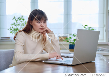 College student girl sitting at desk using computer, typing on a keyboard College student girl sitting at desk using computer, typing on a keyboard 113365588