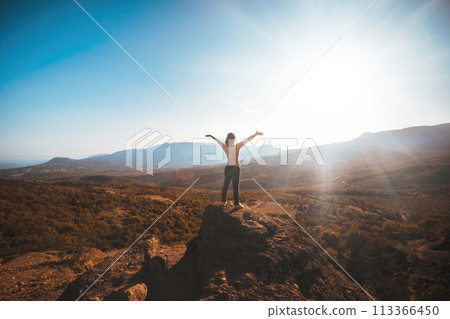 The girl looks at the mountains while facing the sun. High quality photo 113366450