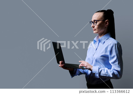Middle-aged business confident woman using laptop on gray background 113366612