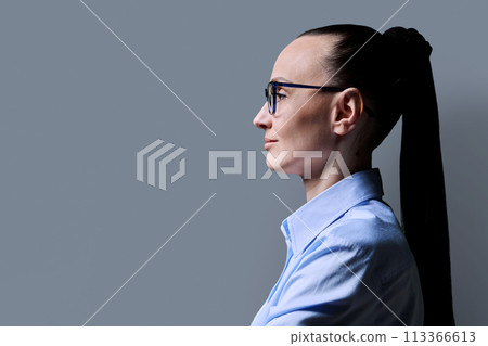 Profile view of 30s serious woman, gray background, copy space Profile view of 30s serious woman, gray background, copy space 113366613