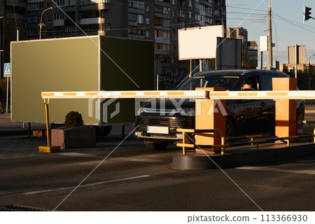 Car approaching to automatic barrier gates for supermarket parking lot. Security system for car park entry to shopping mall. Vehicle entrance with boom barriers and control tickets machine 113366930