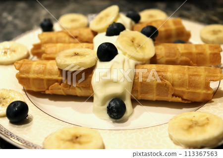 Breakfast waffle rolls and bananas with berries on a beautiful plate. Top view. 113367563