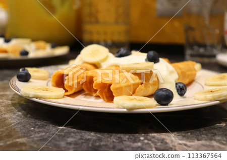 Breakfast waffle rolls and bananas with berries on a beautiful plate. Top view. 113367564