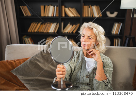 Love yourself. Beautiful old mature woman enjoying mirror reflection. Senior adult older lady looking at mirror confident happy on sofa at home. Woman doing daily morning beauty routine. Self love Love yourself. Beautiful old mature woman enjoying mirror reflection. Senior adult older lady looking at mirror confident happy on sofa at home. Woman doing daily morning beauty routine. Self love 113368470