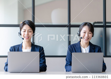 A woman wearing a headset and working on a computer A woman wearing a headset and working on a computer 113368601