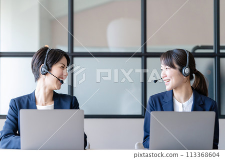 A woman wearing a headset and working on a computer 113368604