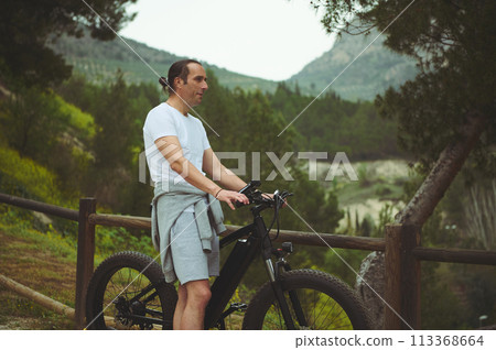 Portrait of a Caucasian young athletic man using electric bike, bicycle, riding in mountains Portrait of a Caucasian young athletic man using electric bike, bicycle, riding in mountains 113368664
