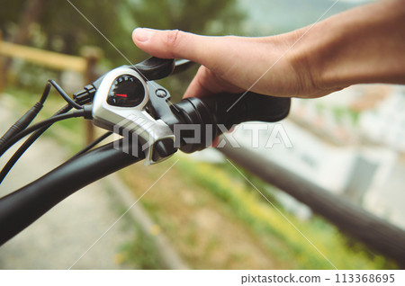 Isolated bicycle brakes in male cyclist's hand. Adjusting bicycle hand brakes while riding cycling on the nature. Close-up view 113368695