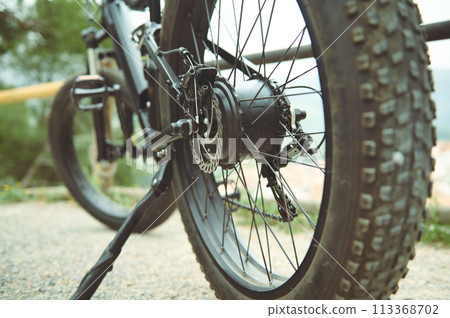 Details of a tubeless electric mountain bike tire standing on the side of the road. View from below. Low viewing angle. Selective focus 113368702