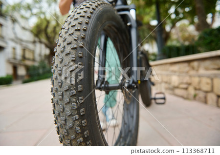 Selective focus on tubeless tire of an electric motor bike, mountain bike. Shallow tread of a bicycle tubeless tire. Cropped view of electric bike bicycle wheel. Copy ad space 113368711