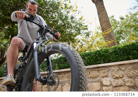 Bottom view of young sporty man riding an electric motor bike in the city. 113368714