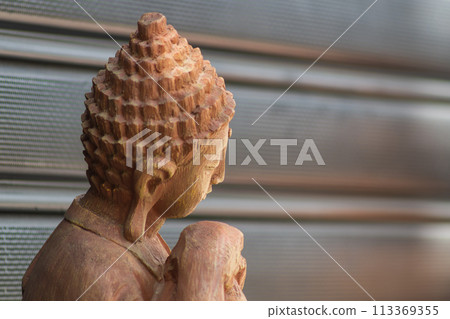A statuette of a person from the Buddhist faith looks to the right against the background of the wall in close-up. There is a copy space A statuette of a person from the Buddhist faith looks to the right against the background of the wall in close-up. There is a copy space 113369355