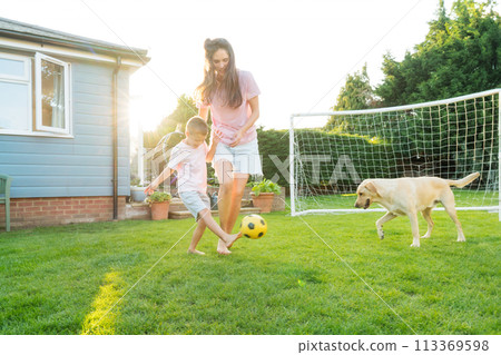 Young mother and son plays soccer with dog and have fun together. Happy family playing football with pet. Fun Playing Games in Backyard Lawn on Sunny Summer Day. Motherhood, childhood, togetherness Young mother and son plays soccer with dog and have fun together. Happy family playing football with pet. Fun Playing Games in Backyard Lawn on Sunny Summer Day. Motherhood, childhood, togetherness 113369598