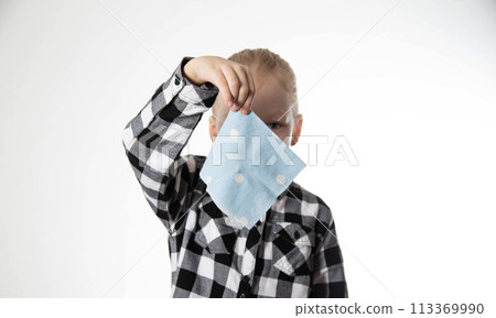 A girl in a checkered shirt holds a handkerchief in her hand against the background of her face. Concept of viral and bacterial runny nose. Allergic rhinitis, colds in children. A girl in a checkered shirt holds a handkerchief in her hand against the background of her face. Concept of viral and bacterial runny nose. Allergic rhinitis, colds in children. 113369990
