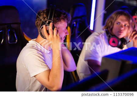Gamers of team puts on headsets at PC computer club, cyber sport tournament. E-sport championship. 5 players in headphones playing video game. Multiplayer online battle, tactical first-person shooter Gamers of team puts on headsets at PC computer club, cyber sport tournament. E-sport championship. 5 players in headphones playing video game. Multiplayer online battle, tactical first-person shooter 113370096