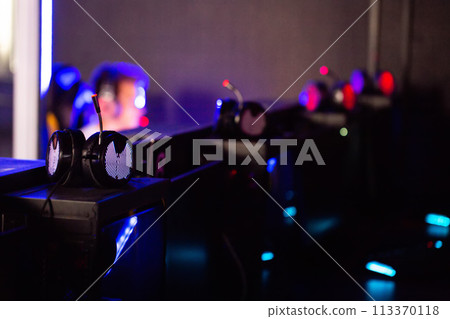 Headphones in focus in a computer club with players in the background. Concept of a tournament and playing computer games. Copy space for text 113370118