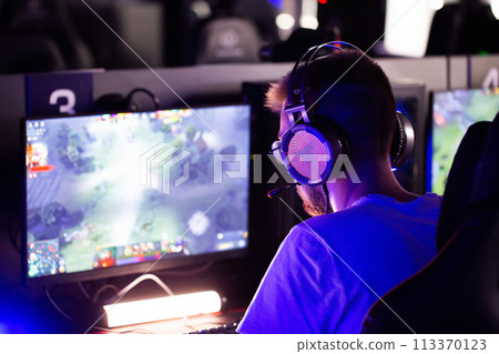 Serious focused teen gamer in headset playing PC video game at computer club during cyber sport tournament. E-sport championship. Modern multiplayer online real-time strategy RTS, tactics skill 113370123