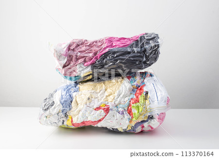 Multi-colored clothes and things packed in vacuum bags for storage on a white background. Modern compact storage technology, close-up 113370164
