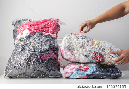 A man's hand tightens the lid of the valve of vacuum bags for storing clothes. Compact storage of things, close-up A man's hand tightens the lid of the valve of vacuum bags for storing clothes. Compact storage of things, close-up 113370165