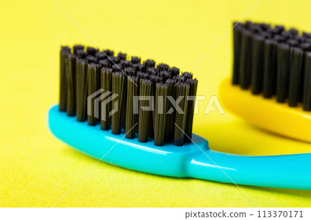 Modern toothbrushes with carbon coating on a yellow background, close-up. Toothbrushes with medium-hard bristles. Oral care and hygiene, macro 113370171