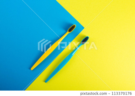 Yellow and blue toothbrush with charcoal coating on a yellow-blue background. The concept of dental and oral hygiene in dentistry. Copy space for text, medium hard. View from above. Prevention of 113370176