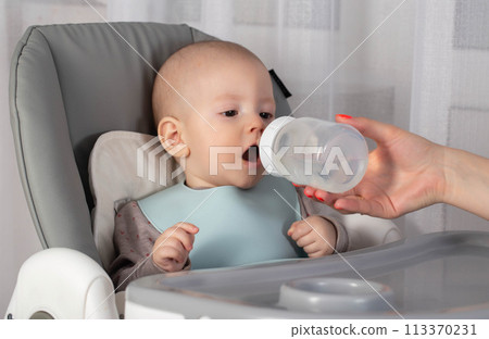 Complementary feeding of the baby with milk formula that replaces breast milk. Close-up Complementary feeding of the baby with milk formula that replaces breast milk. Close-up 113370231