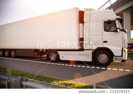 A white modern truck with an isothermal refrigerated semi-trailer transports perishable products in a trailer with a constant temperature regime. Transportation of seafood, fruits and meat. Copy space 113370525