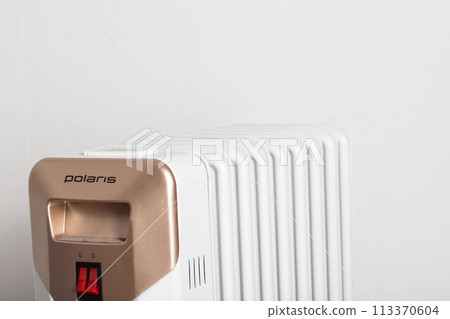 Modern electric oil heating radiator on a white background. The concept of heating a room in cold weather. 113370604