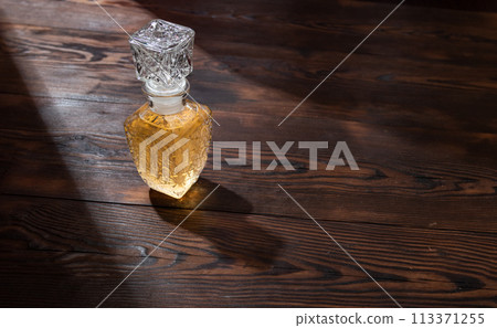 Glass decanter with drink. Whiskey in a decanter. Alcohol in a glass decanter with a pattern. Glass decanter with drink. Whiskey in a decanter. Alcohol in a glass decanter with a pattern. 113371255