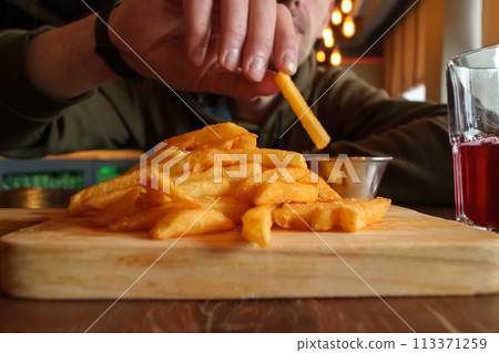 Close-Up of French Fries on Cutting Board, selective focus Close-Up of French Fries on Cutting Board, selective focus 113371259