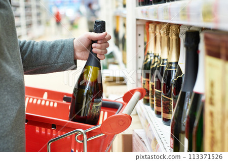 Bottle of champagne in hand at store 113371526