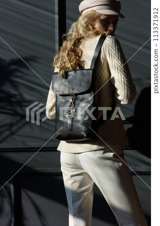 Studio portrait of beautiful woman with a curly blond hair holding brown bag, posing on gray background. Studio portrait of beautiful woman with a curly blond hair holding brown bag, posing on gray background. 113371912