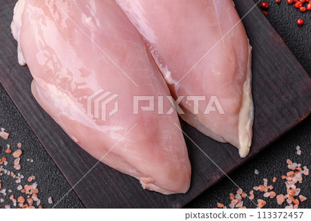 Fresh chicken fillet on a dark concrete table with spices and herbs Fresh chicken fillet on a dark concrete table with spices and herbs 113372457