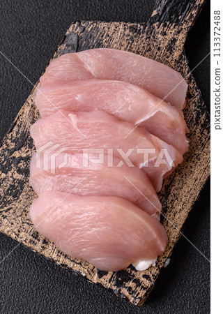 Slices of raw chicken or turkey fillet with salt, spices and herbs Slices of raw chicken or turkey fillet with salt, spices and herbs 113372488