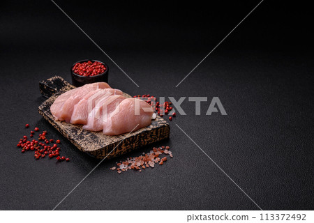 Slices of raw chicken or turkey fillet with salt, spices and herbs 113372492