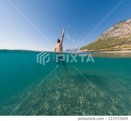 Underwater and surface split view in tropics paradise with happy man, under and above waterline, beautiful view on tropical sea. Turkey . snorkeling vacation concept Underwater and surface split view in tropics paradise with happy man, under and above waterline, beautiful view on tropical sea. Turkey . snorkeling vacation concept 113372684