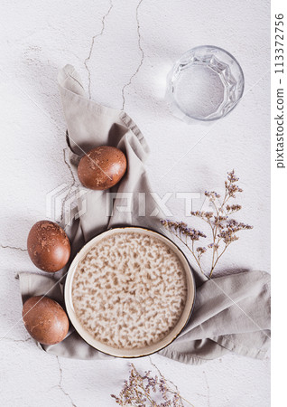 Naturally colored Easter eggs, plate, cutlery and glass of water on the table top and vertical view 113372756