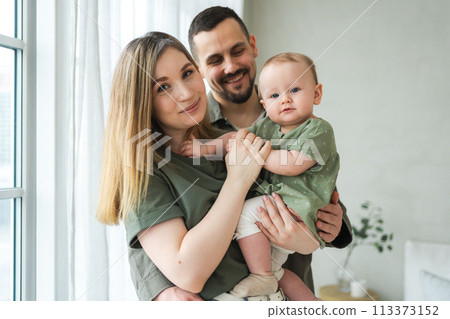 Happy family at home. Mother father holding little toddler child. Mom dad baby girl relax playing having fun together. Woman man hugging embracing baby with love care. Parent of breast feeding baby 113373152