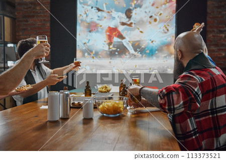 Friends coming together to watch an online football match on TV, with beer and snacks adding to the enjoyment of the game. 113373521