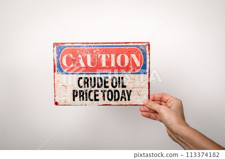 Crude Oil Price Today. Metal warning sign in a woman's hand on a white background Crude Oil Price Today. Metal warning sign in a woman's hand on a white background 113374182