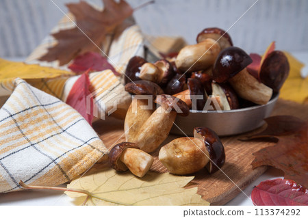 Several Imleria Badia or Boletus badius mushrooms commonly known as the bay bolete and vintage pan with mushrooms on wooden cutting board.. 113374292