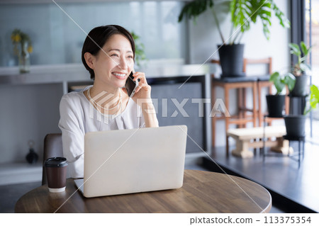 Beautiful middle-aged woman talking on the phone while working in a beautiful company, office or coworking space Beautiful middle-aged woman talking on the phone while working in a beautiful company, office or coworking space 113375354