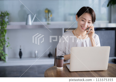 Beautiful middle-aged woman talking on the phone while working in a beautiful company, office or coworking space Beautiful middle-aged woman talking on the phone while working in a beautiful company, office or coworking space 113375355