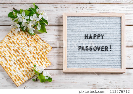 Happy Passover flatlay. Jewish matzo bread and flowers on white wooden background. Happy Passover flatlay. Jewish matzo bread and flowers on white wooden background. 113376712
